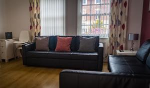 a living room with a black leather couch and a window at The Racecourse Gathering in Chester