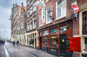 een straat met gebouwen en mensen die over een straat lopen bij The Old Nickel Hotel in Amsterdam