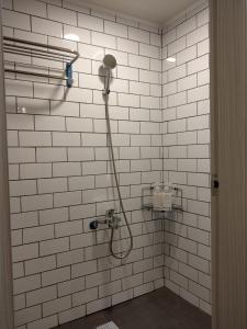 Baño de azulejos blancos con ducha y manguera en Mini Voyage Hostel en Hualien
