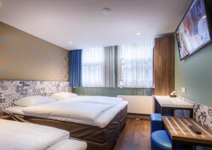 a hotel room with two beds and a desk and a table at The Old Nickel Hotel in Amsterdam