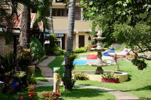 un jardín con una fuente frente a un edificio en Pousada Oasis, en Pipa