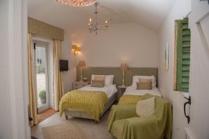 a bedroom with two beds and a chair and a chandelier at Bridleway Bed & Breakfast in Lincoln