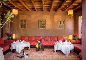 uma sala de estar com um sofá vermelho e duas mesas em Jnane Leila em Marrakech