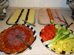 Luxury Hotel Siófok في سيوفوك: طبقين من اللحوم والخضار على طاولة