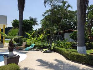 a patio with chairs and a pool with palm trees at Residencia Jacarandas in Cuernavaca