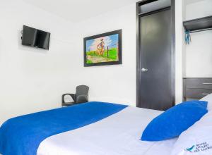 a bedroom with a blue and white bed and a tv at Hotel Azulejo del Llano in Yopal