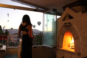 ギョレメにあるMirzade Konak Hotelの暖炉を見るバルコニーに立つ女性