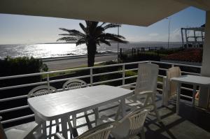 una mesa blanca y sillas en un balcón con vistas al océano en Los Sargos, en Punta del Este