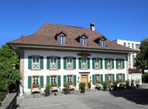 a large white building with green shutters at Romantik Hotel Landhaus Liebefeld in Bern