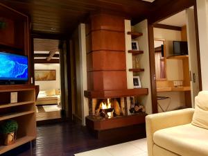 sala de estar con chimenea y TV en Luxuoso Flat Mountain Village, en Canela