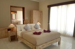 a bedroom with a large bed with purple bows on it at The Bali Shanti in Ubud