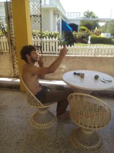 a man sitting in a chair next to a table at Leslies' Home in Portmore