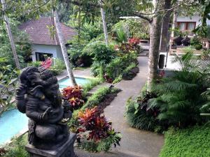 a statue in a garden next to a pool at The Bali Shanti in Ubud