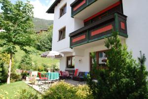 ein Haus mit einer Terrasse mit einem Tisch und Stühlen in der Unterkunft Haus Gamberg in Sankt Anton am Arlberg