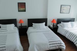 1 dormitorio con 2 camas con sábanas blancas y lámparas rojas en Hotel Real Estación, en Bogotá