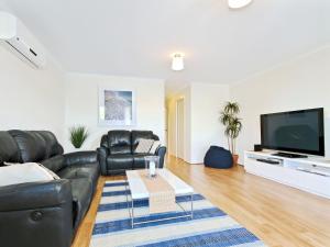 a living room with black leather furniture and a flat screen tv at Sunset at Snapper Point - Aldinga Beach - C21 SouthCoast Holidays in Aldinga Beach