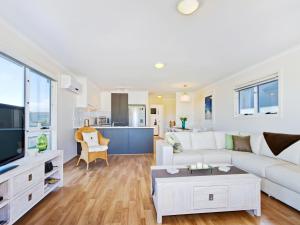 a living room with a white couch and a kitchen at Sunset at Snapper Point - Aldinga Beach - C21 SouthCoast Holidays in Aldinga Beach