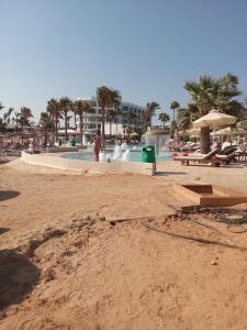 a beach with a swimming pool with people and palm trees at SUNSHINE APTS, TWO BEDROOM , FREE INTERNET, No 3 in Ayia Napa