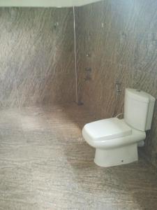 a bathroom with a white toilet and a wall at Walawe Park View Hotel in Udawalawe
