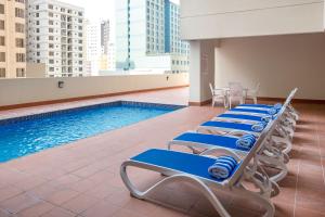 a row of lounge chairs next to a swimming pool at Aspire Tower in Manama
