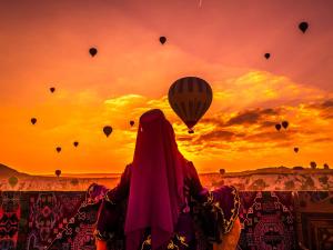 Una donna che guarda le mongolfiere al tramonto di Vineyard Cave Hotel a Göreme