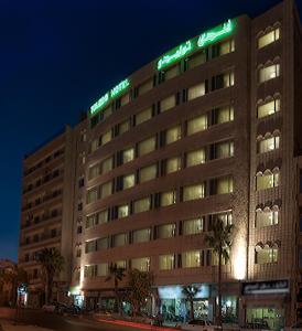 a hotel building with a sign on it at night at Toledo Amman Hotel in Amman