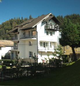 a white building with a fence in front of it at Pensiunea Carina in Bran