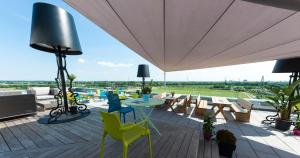 eine Terrasse mit einem Tisch, Stühlen und einem Sonnenschirm in der Unterkunft BEST WESTERN Hotel The K Unterföhring in München
