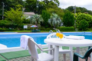 uma mesa branca e cadeiras ao lado de uma piscina em Le Nessa Jyogasaki em Ito
