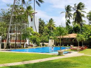 a pool in front of a building with palm trees at Sanmira Renaissance in Unawatuna