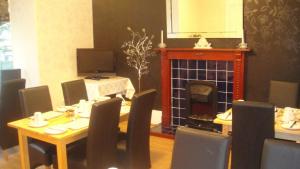 a dining room with a table and chairs and a fireplace at Station View Guest House in Dyce