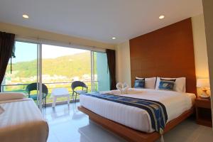 a bedroom with a large bed and a large window at Good Nice Hotel in Patong Beach