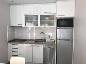 a kitchen with white cabinets and a stainless steel refrigerator at Rosa House in Nazaré