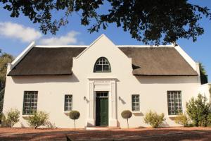 a white house with a black roof and a green door at Rothman Manor in Swellendam