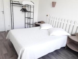 a white bed with two pillows and a table at Au Nouvel H&ocirc;tel in Toulon