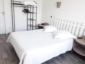 uma cama branca com duas almofadas e uma mesa em Au Nouvel Hôtel em Toulon