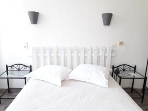 uma cama branca com duas almofadas e duas mesas em Au Nouvel Hôtel em Toulon