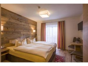 ein Hotelzimmer mit einem großen Bett mit einer Holzwand in der Unterkunft Pension Waldegg in Hippach