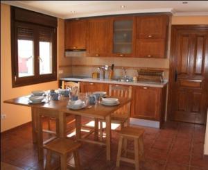 a kitchen with a wooden table and chairs in it at Apartamentos Casa Bernabé in Miengo