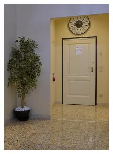 a white door with a clock above it next to a plant at Domus Dea in Venice