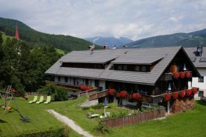 una casa en una colina con montañas en el fondo en Ferienwohnungen Schnarf, en Valdaora