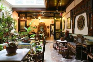 un restaurante con mesas, sillas y plantas en 5 Heeren Museum Residence en Melaka