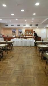 a man standing in a dining room with tables and chairs at Apartmán 401 - Hotel s apartmánmi CROCUS . in Štrbské Pleso