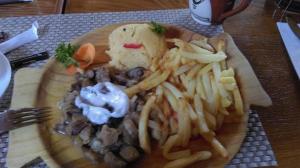 a plate of food with meat and french fries at Camere de închiriat AnneMaryy in Arbore