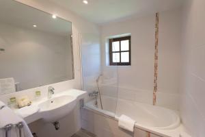 y baño blanco con bañera, lavamanos y ducha. en Les Hospitaliers, en Le Poët-Laval
