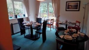 a dining room with tables and chairs and windows at Bluebell Cottage in Tarbert