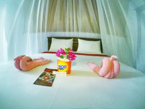 three stuffed animals sitting on a bed with a flower pot at Ina Gili Guesthouse in Gili Islands