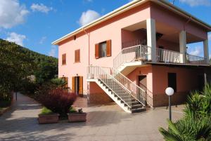 um grande edifício rosa com escadas em frente em B&B ARENOSU25 em Alghero