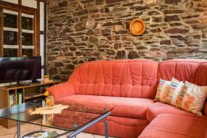 a living room with a red couch and a stone wall at Ferienhaus Marie in Bremm