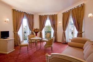 a living room with a couch and a table and chairs at Grand Hôtel Moderne in Lourdes